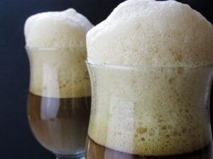 Två glas mörk dryck med höga, täta skumkronor