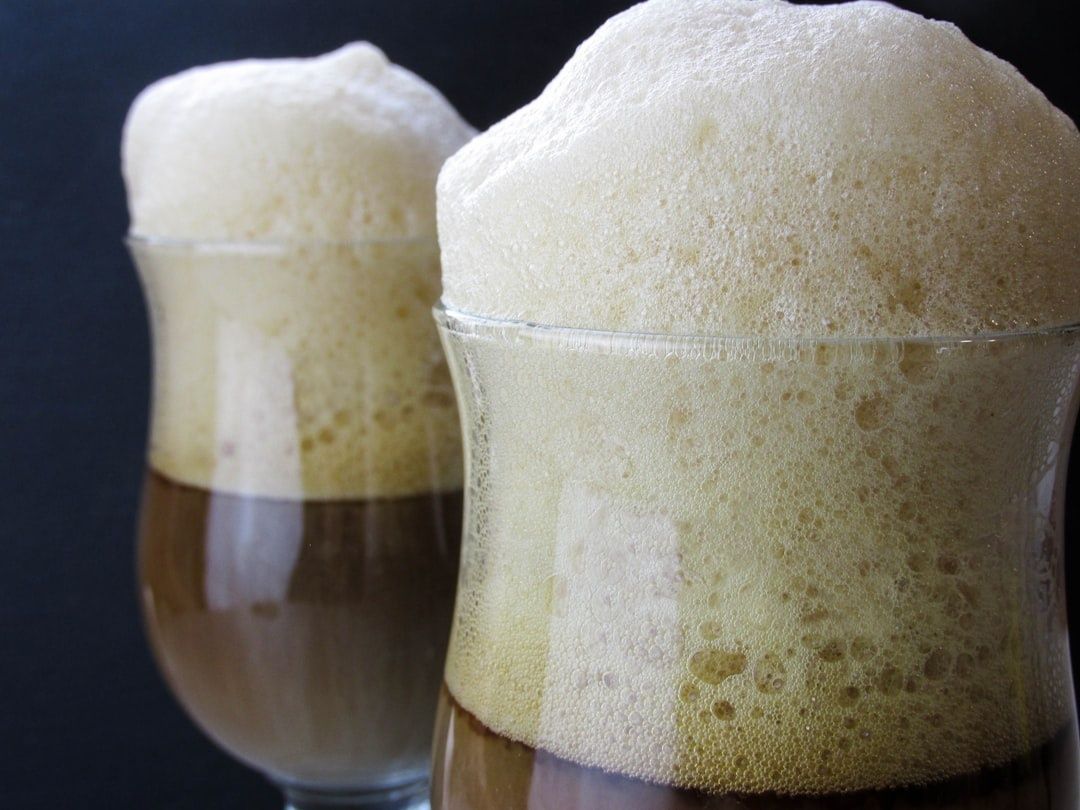 Två glas mörk dryck med höga, täta skumkronor